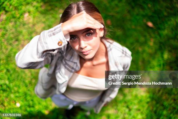 young latino woman standing on grass, looking up at the camera - mexico city, high angle - elevated view portrait stock pictures, royalty-free photos & images