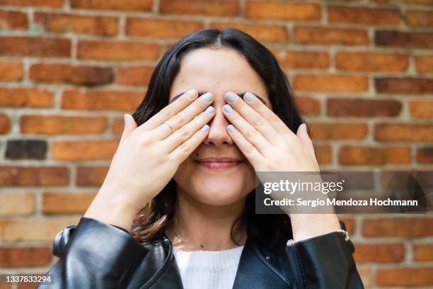 young latino woman covering her eyes, see no evil - blind date stock pictures, royalty-free photos & images