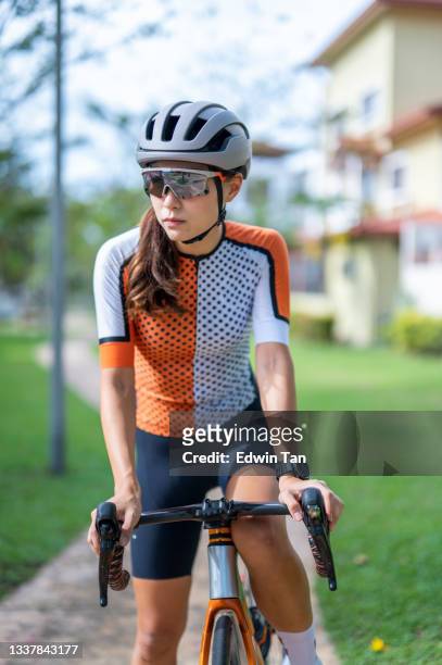 portrait asian chinese female cyclist looking away with cool attitude at public park with her road bike cycling - cycling shorts stock pictures, royalty-free photos & images