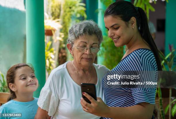 young woman showing a cell phone to an old woman and a girl look,santa clara,cuba - clara cell stock pictures, royalty-free photos & images