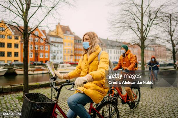 reiseleiterin und ihre gruppe erkunden die stadt auf den fahrrädern während der pandemie - public transport denmark stock-fotos und bilder