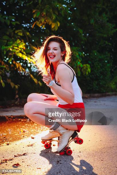 femme sur des patins à roulettes blancs rétro souriant à la caméra pointant du doigt comme des fusils. - pin up danse photos et images de collection
