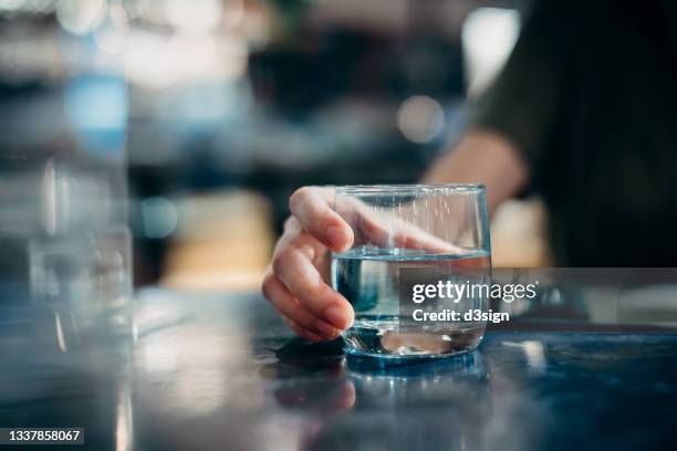close up of young woman drinking a glass of water while sitting in dining table in restaurant. healthy lifestyle and stay hydrated - conference dining table stockfoto's en -beelden
