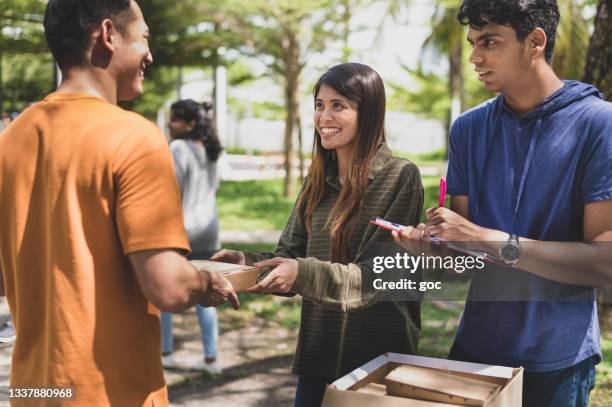 volunteers giving out free packed of food during the charity drive community food bank outdoors. - ngo imagens e fotografias de stock