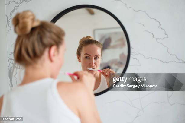 woman brushing teeth in bathroom - zähne putzen frau stock-fotos und bilder
