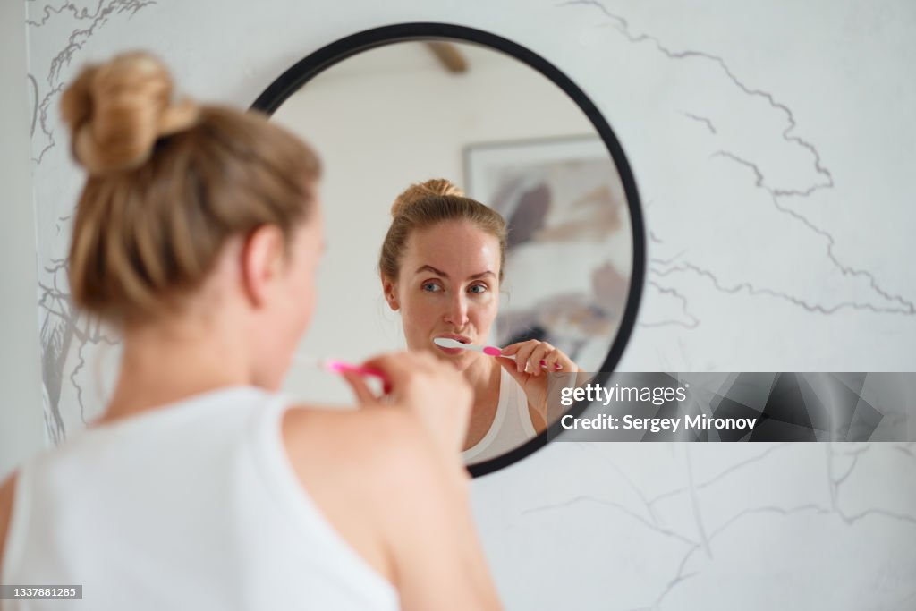 Woman brushing teeth in bathroom