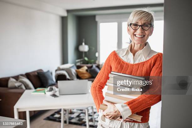 porträt eines professors zu hause, der bücher hält und lächelt - education retirement stock-fotos und bilder