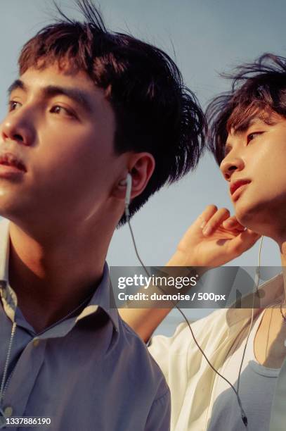 low angle view of young man listening to music against sky,vietnam - modern vietnam stockfoto's en -beelden