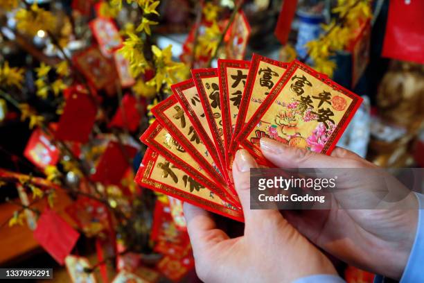 Tu An pagoda. Buddhist woman with red envelopes on yellow tree for Chinese and Vietnamese New Year. Red color is a symbol of good luck. Saint Pierre...