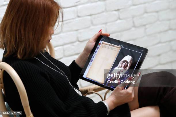 Woman praying the Rosary on a digital tablet Ipad. France.