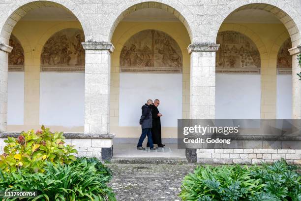 Lay man and benedictine monk in San Pietro di Sorres basilica cloister, Sardinia, Italy.