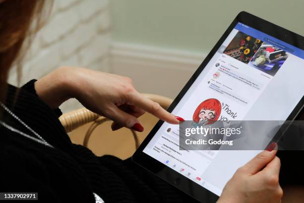 Woman reading facebook on an Apple iPad digital tablet. Facebook social media app. France.