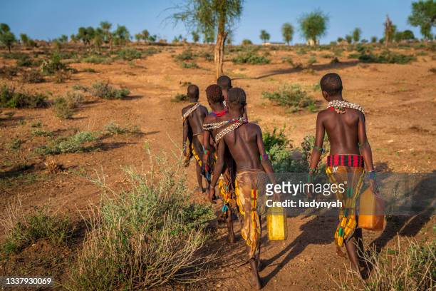 afrikanische mädchen, die wasser aus dem brunnen tragen, äthiopien, afrika - african girl drinking water stock-fotos und bilder