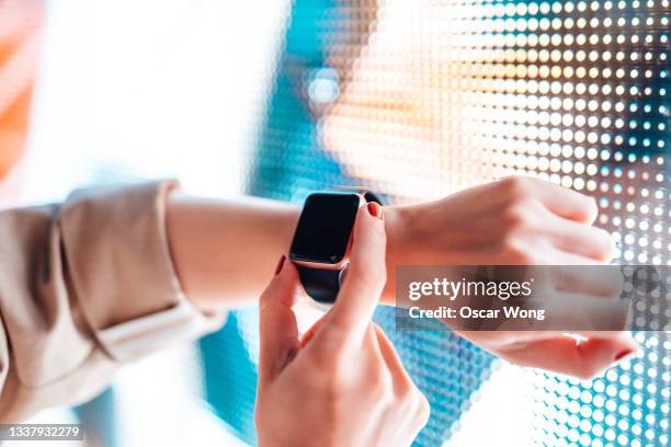 woman using smart watch against colourful neon light display - reloj inteligente fotografías e imágenes de stock