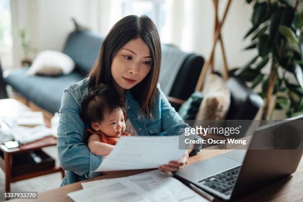 young mother with baby daughter working from home - madre capofamiglia foto e immagini stock