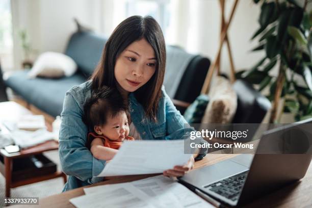 young mother with baby daughter working from home - bank statement bildbanksfoton och bilder