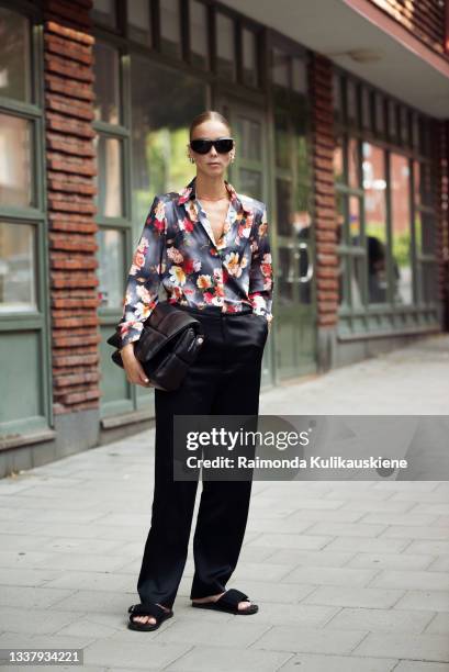 Hilda Sandstrom wearing grey silk shirt with flowers and black pants holding black bag outside HOPE during Stockholm Fashion Week Spring/Summer 2022...