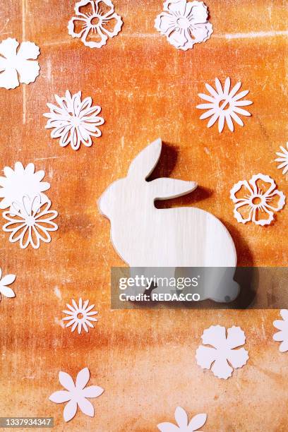 Easter bunny rabbit with different paper flowers around over orange stone background. Flat lay. Copy space. Easter holiday greeting card concept.