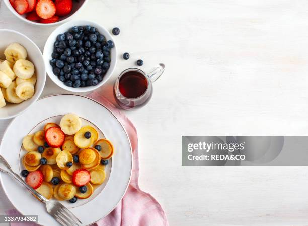 Trendy food - pancake cereal. Home breakfast with tiny pancakes and berries. View from above.