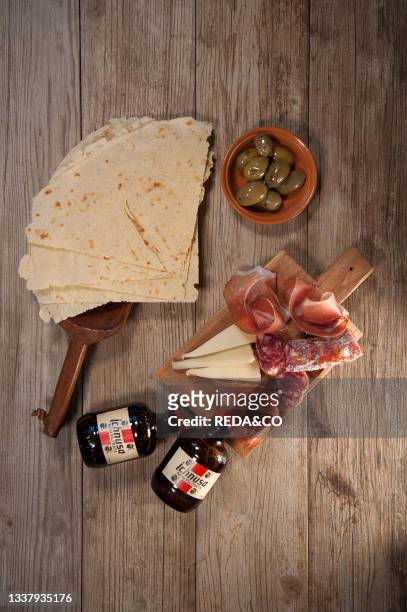 Sardinian raw ham. Sardinian raw pork sausage. Sardinian pecorino cheese plate. Olives. Carasau Bread. Unfiltered Ichnusa beer. Sardinia. Italy....
