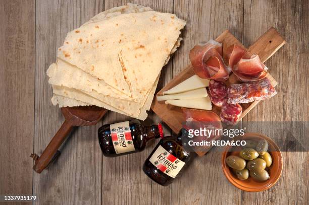 Sardinian raw ham. Sardinian raw pork sausage. Sardinian pecorino cheese plate. Olives. Carasau Bread. Unfiltered Ichnusa beer. Sardinia. Italy....