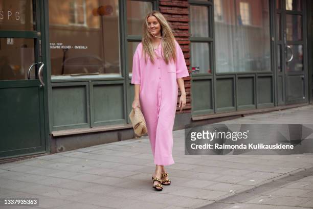 Guest wearing pink dress, beige bag and high heels outside HOPE during Stockholm Fashion Week Spring/Summer 2022 on September 02, 2021 in Stockholm,...