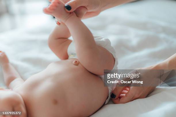 mother checking if diaper is too tight after changing - baby close up bed stockfoto's en -beelden