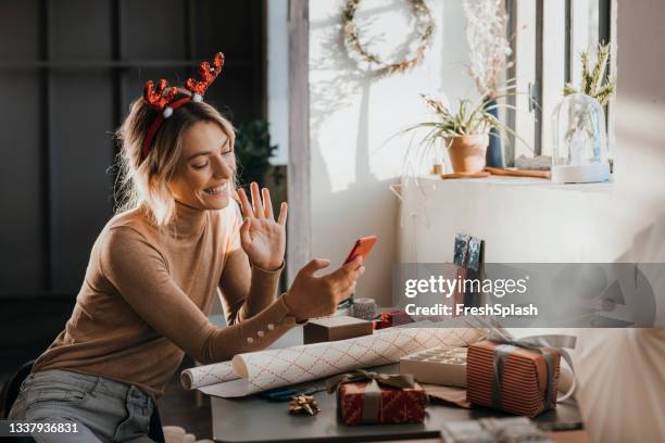 cheerful woman talking on video call with friend - woman blond looking left window stockfoto's en -beelden