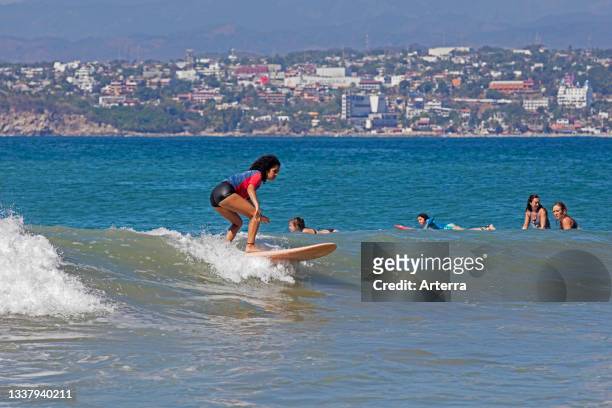 Young female surfers riding breaking wave on surfboards at Playa Zicatela near Puerto Escondido, San Pedro Mixtepec, Oaxaca, Mexico.
