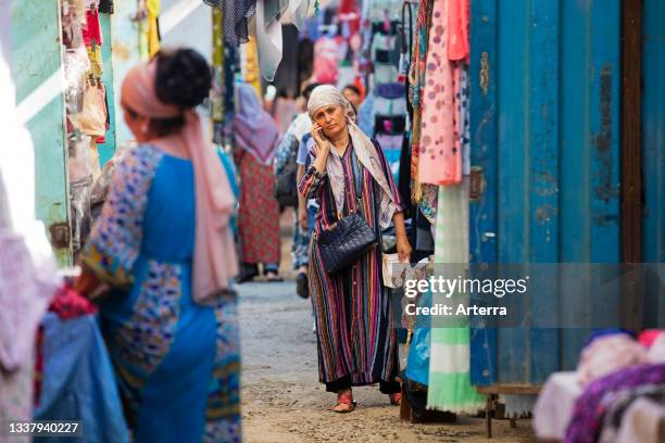 Kyrgyz woman with headscarf calling with smartphone at market in the city Osh, Kyrgyzstan.