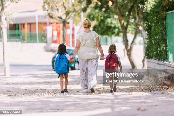 mother and daughters with their backs turned, go hand in hand on the way to school. concept of education and back to school. - enfant cartable photos et images de collection