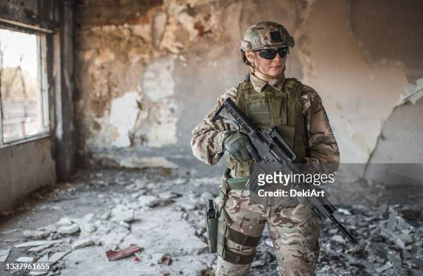 une femme soldat des forces spéciales avec un fusil dans un entrepôt abandonné - stealth stock photos et images de collection