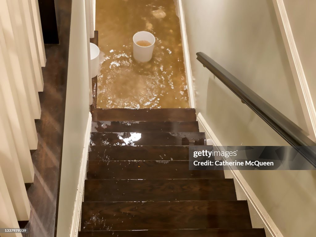 Flood water flowing down staircase into house basement