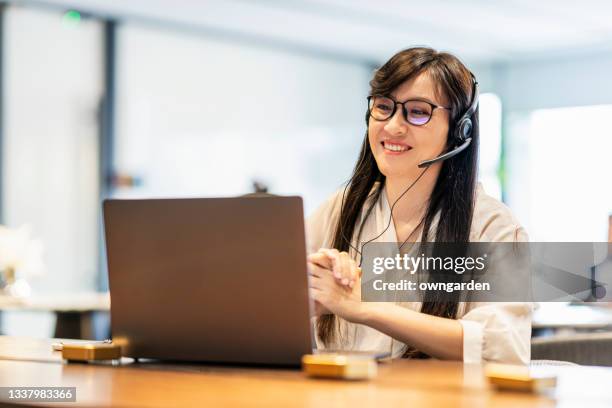 confident asian businesswoman talking to the camera video calling video conference with his business partners in office. - klanten georiënteerd stockfoto's en -beelden