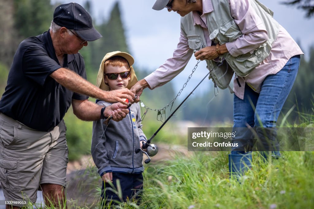 Cute Redhead Boy and Grandparents Fishing in the River in Quebec