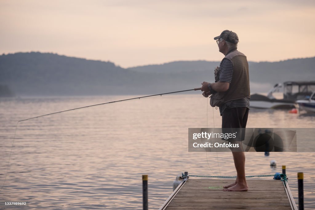 Senior Man Fliegenfischen bei Sonnenuntergang