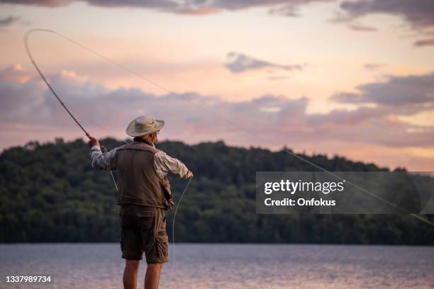 senior man fliegenfischen bei sonnenuntergang - bass stock-fotos und bilder