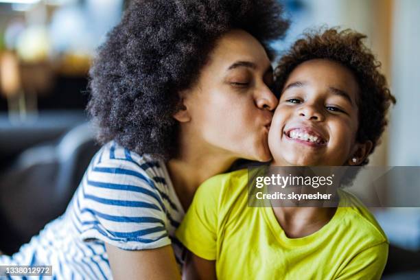 madre negra amorosa besando a su pequeña hija en casa. - friends kissing cheeks fotografías e imágenes de stock