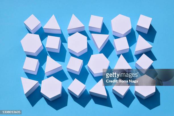white paper cubes and prisms on blue background - tvådimensionell form bildbanksfoton och bilder