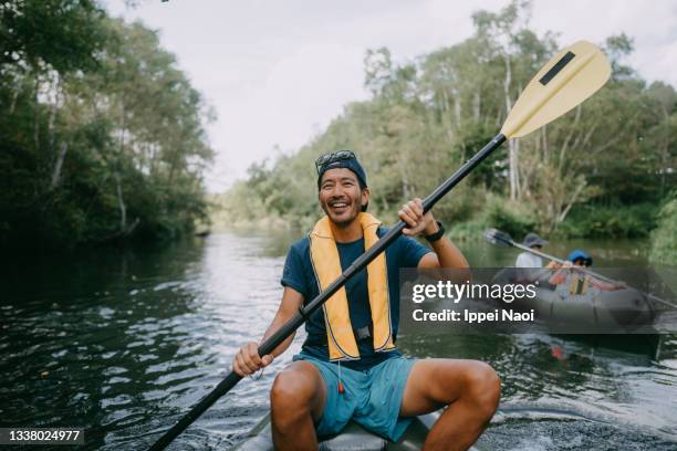 happy man paddling kayak through river, hokkaido, japan - piragüismo y canotaje fotografías e imágenes de stock