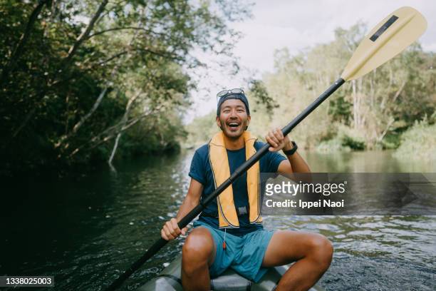 cheerful man paddling kayak through river, hokkaido, japan - andare in canoa foto e immagini stock