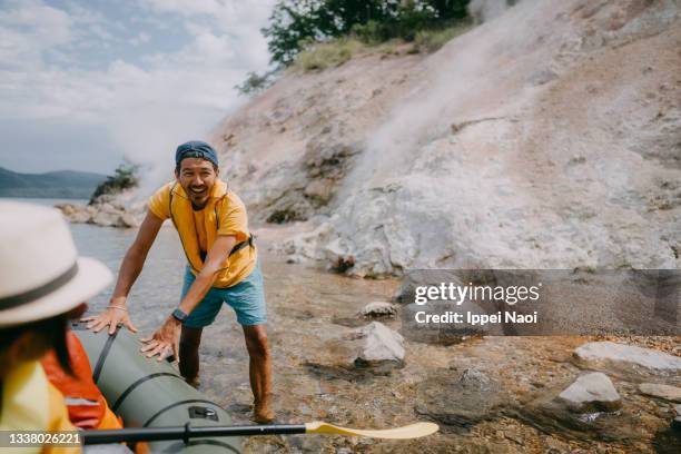 man pushing kayak on lake with hot spring, hokkaido, japan - rubber boat stock pictures, royalty-free photos & images