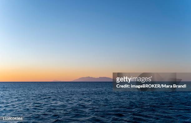 sunset over the neer, silhouette of an island in the back, kos, dodecanese, greece - dodecanese islands stock-fotos und bilder