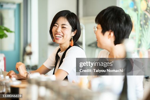 A woman talking with a friend at the counter of a cafe A woman talking with a friend at the counter of a cafe