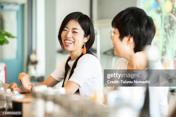 a woman talking with a friend at the counter of a cafe - japanese ethnicity 個照片及圖片檔