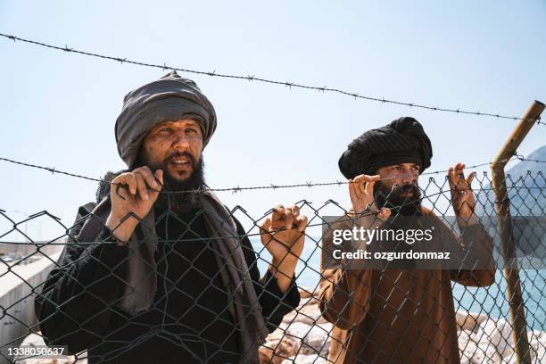 hombre refugiado de pie detrás de la valla - valla de alambre fotografías e imágenes de stock