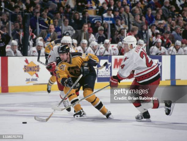 Jason Allison of Canada and Center for the Boston Bruins in motion on the ice skates past Sami Kapanen of the Carolina Hurricanes during their NHL...