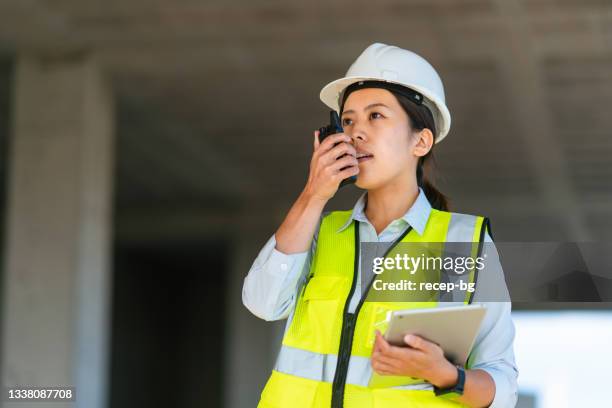 young female engineer using walkie-talkie on construction site - project manager stock pictures, royalty-free photos & images