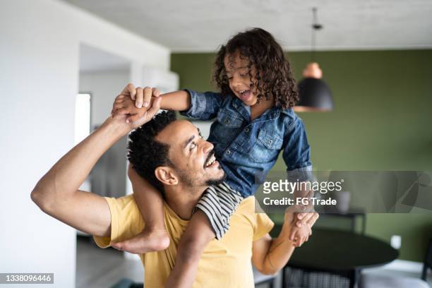 father carrying son over shoulders at home - on shoulders stock pictures, royalty-free photos & images