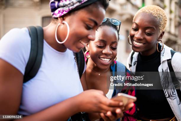 young women looking at mobile phone - black people group stockfoto's en -beelden